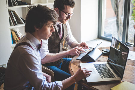 two young hipster stylish elegant men working with notebook and tablet at home 