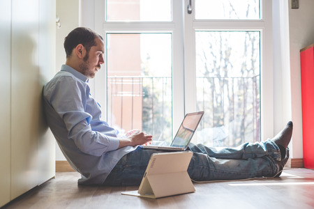 elegant business multitasking multimedia man using devices at homeの写真素材