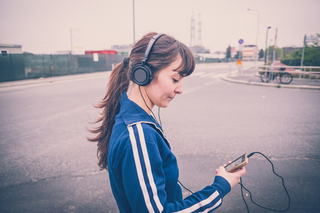 beautiful woman walking and listening music in a desolate lurban landscapeの写真素材