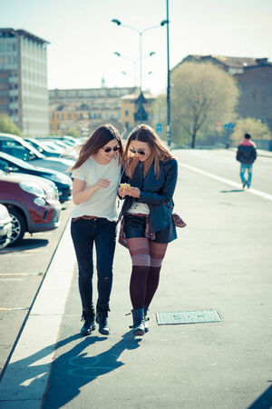 two beautiful young women using smart phone in the cityの写真素材