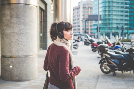 young beautiful hipster woman listening music with headphones in the cityの写真素材