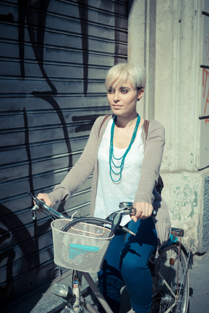 beautiful young blonde short hair hipster woman witk bike in the cityの写真素材