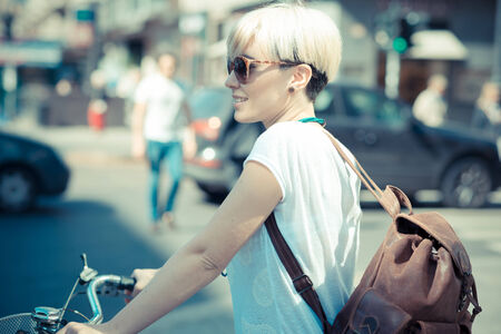 beautiful young blonde short hair hipster woman with bike in the cityの写真素材