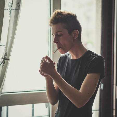 young lesbian stylish hair style woman smoking at home の写真素材