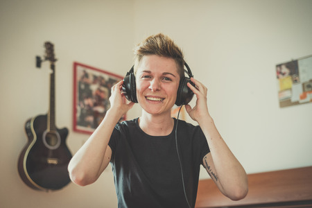 young lesbian stylish hair style woman listening to music at home の写真素材