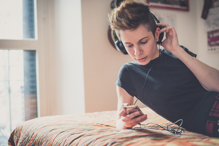 young lesbian stylish hair style woman listening to music at home の写真素材