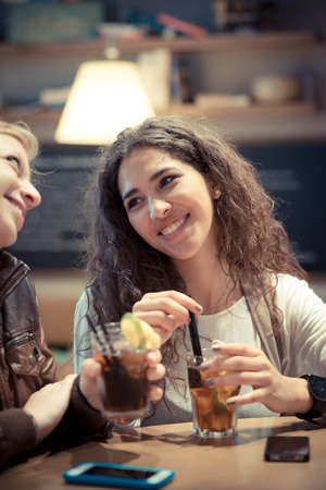 blonde and brunette beautiful stylish young women at the barの写真素材