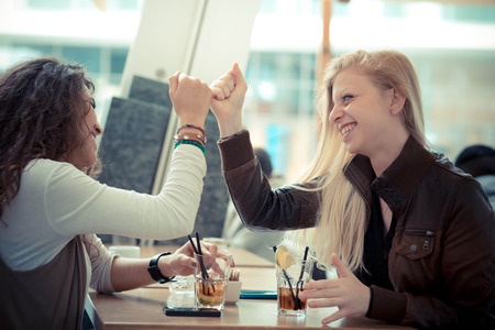 blonde and brunette beautiful stylish young women at the barの写真素材