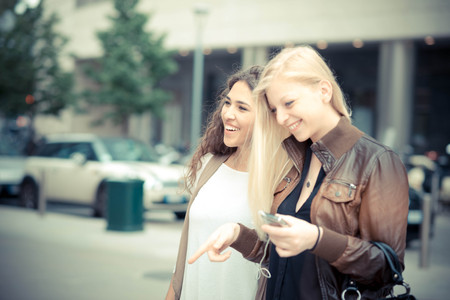 blonde and brunette beautiful stylish young women in the cityの写真素材