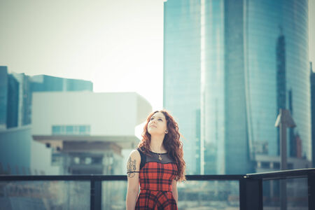 young beautiful hipster woman with red curly hair in the cityの写真素材