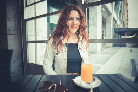 young beautiful hipster woman with red curly hair at the barの写真素材
