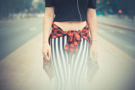young beautiful hipster woman with red curly hair listening music in the cityの写真素材