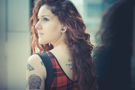 young beautiful hipster woman with red curly hair in the cityの写真素材