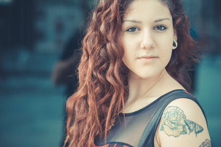 young beautiful hipster woman with red curly hair in the cityの写真素材