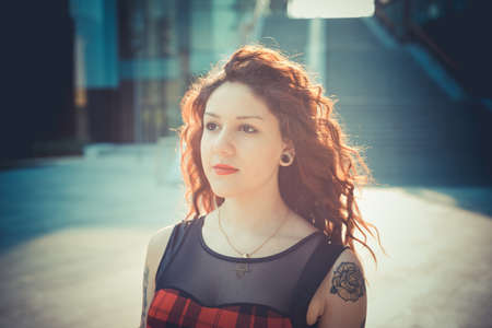 young beautiful hipster woman with red curly hair in the cityの写真素材