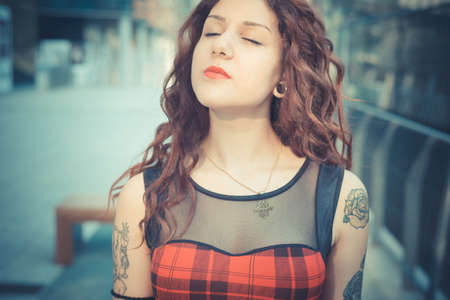 young beautiful hipster woman with red curly hair in the cityの写真素材