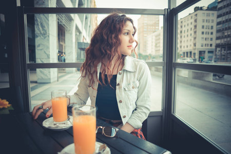 young beautiful hipster woman with red curly hair at the barの写真素材