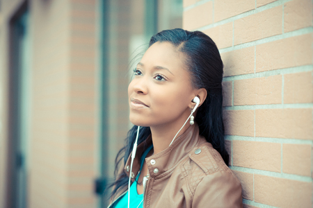 beautiful african young woman listening music earphones in the cityの写真素材