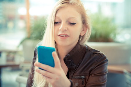 beautiful young blonde woman using smart phone in the cityの写真素材