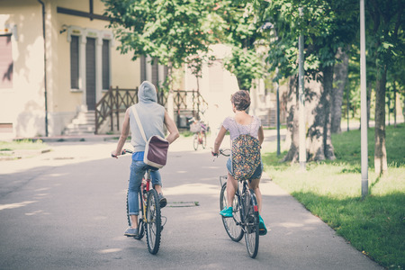 couple of friends young  man and woman riding bike in the cityの写真素材