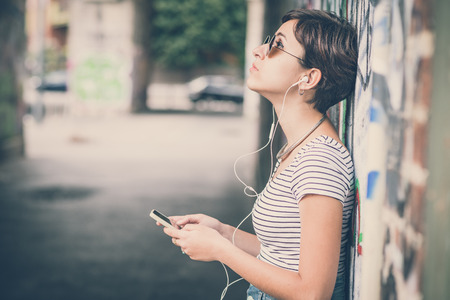 young hipster woman listening to music in the cityの写真素材
