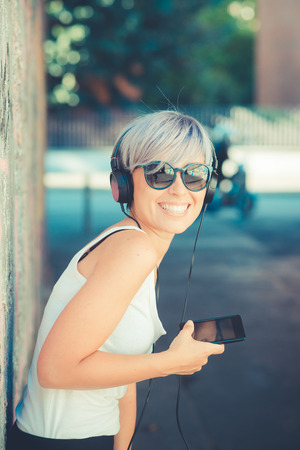 young beautiful short blue hair hipster woman with headphones music in the cityの写真素材