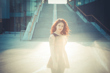 young beautiful hipster woman with red curly hair in the cityの写真素材