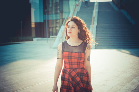 young beautiful hipster woman with red curly hair in the cityの写真素材