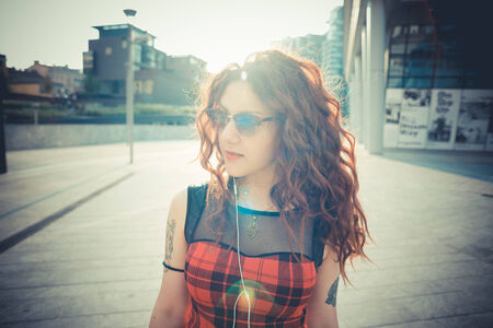 young beautiful hipster woman with red curly hair in the cityの写真素材