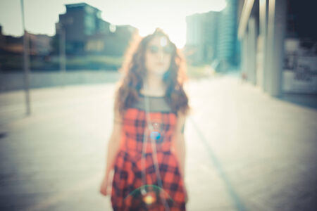 young beautiful hipster woman with red curly hair in the cityの写真素材