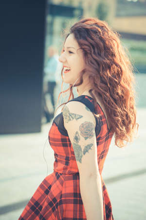 young beautiful hipster woman with red curly hair in the cityの写真素材