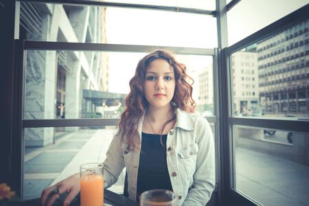 young beautiful hipster woman with red curly hair at the bar