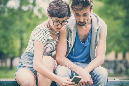 couple of friends young  man and woman using smartphone in the cityの写真素材