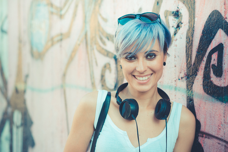 young beautiful short blue hair hipster woman with headphones music in the cityの写真素材
