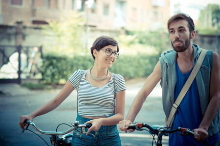 couple of friends young  man and woman riding bike in the cityの写真素材