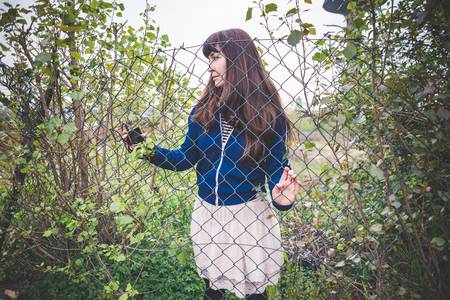 beautiful woman behind a grid in a desolate lurban landscape