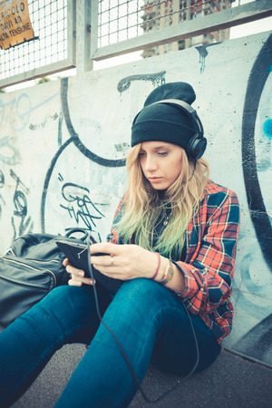 beautiful young blonde hair woman hipster listening music in the cityのeditorial素材