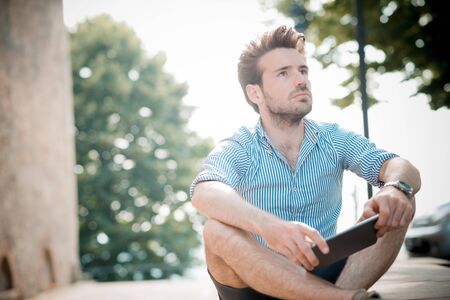young handsome hipster modern man outdoor using tablet in summertimeの写真素材