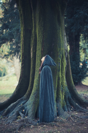 beautiful dark vampire woman with black mantle and hood halloweenの写真素材
