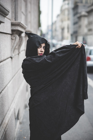 beautiful dark vampire woman with black mantle and hood halloweenの写真素材