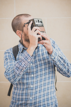 handsome hipster casual multitasking modern man with vintage camera in the cityの写真素材
