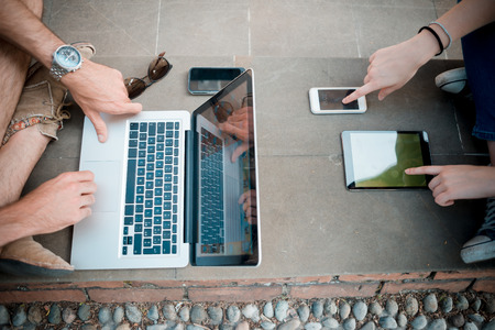 young couple using technology multitasking smarpthone tablet and notebook in the streetの写真素材
