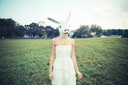 rabbit mask absurd beautiful young woman with white dress in the cityの写真素材