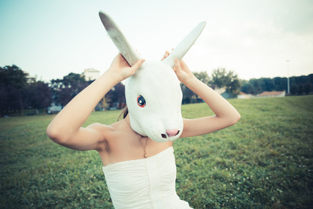 rabbit mask absurd beautiful young woman with white dress in the cityの写真素材