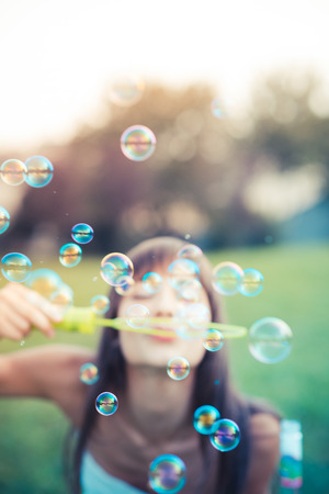 beautiful young woman with white dress blowing bubble in the cityの写真素材