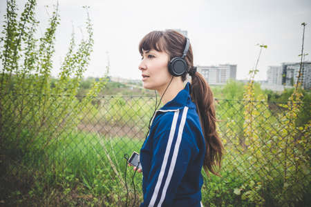 beautiful woman walking and listening music in a desolate lurban landscapeの写真素材