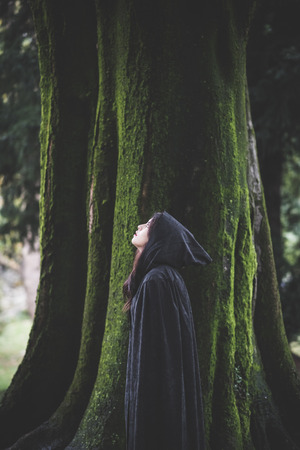 beautiful dark vampire woman with black mantle and hood halloweenの写真素材