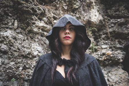 beautiful dark vampire woman with black mantle and hood halloweenの写真素材