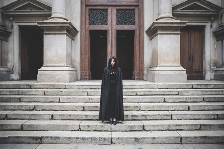 beautiful dark vampire woman with black mantle and hood halloweenの写真素材