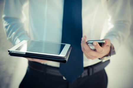close up businessman man hand using tablet and smart phone device outdoorの写真素材